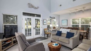 Ein Wohnzimmer mit Fernseher, Sofas, einem Couchtisch und einem Essbereich mit Tisch und Stühlen.