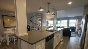 Una cocina moderna con una isla central, iluminación colgante y vistas al exterior.
