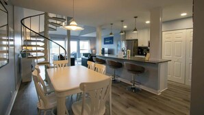 Una cocina moderna con una isla central, taburetes de bar e iluminación colgante.