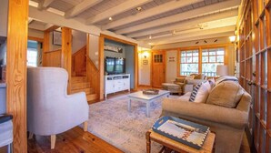 Ein geräumiges Wohnzimmer mit einer Holztreppe, einem Fernseher und einer gemütlichen Sitzecke.