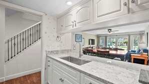 A kitchen with white cabinets, a marble countertop, and a built-in sink.