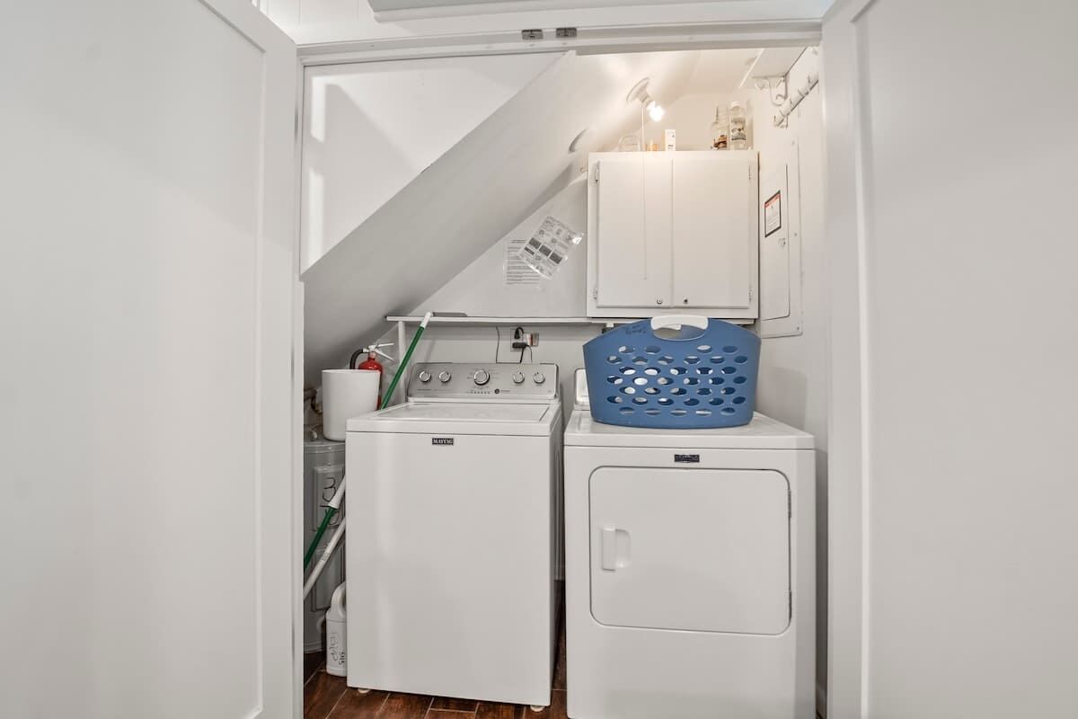 A laundry room with a washing machine, dryer, and a blue laundry basket.