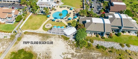 An aerial view of Fripp Island Beach Club with multiple swimming pools, a beach area, and surrounding residential buildings.