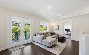 Een moderne woonkamer met een modulaire bank, een salontafel en uitzicht op een balkon met begroeiing.