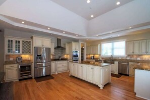 A spacious kitchen with white cabinetry, stainless steel appliances, and a large island. - 719 Sea Dragon Lane - Robin's Nest (Fripp Island)