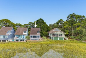 A row of houses with a large body of water in the foreground, surrounded by trees.