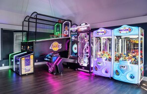 Una hilera de máquinas de videojuegos arcade, incluyendo baloncesto y juegos de garra, con un aro de baloncesto y una exhibición de recuerdos de los Lakers de la NBA.