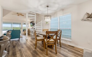 A dining area with a wooden table and chairs, a staircase, and a view of the outdoors. - 1 Periwinkle Ct (Fripp Island)