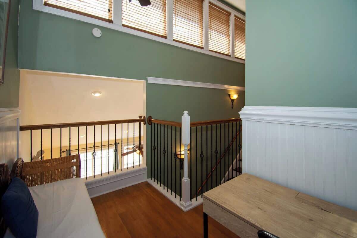 A staircase with a wooden handrail, a white balustrade, and a wall-mounted light fixture.