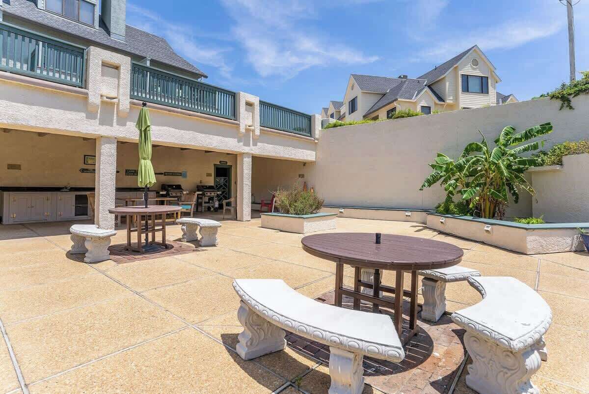Une cour avec des espaces de détente en plein air, une piscine et un espace couvert équipé d’une cuisine.