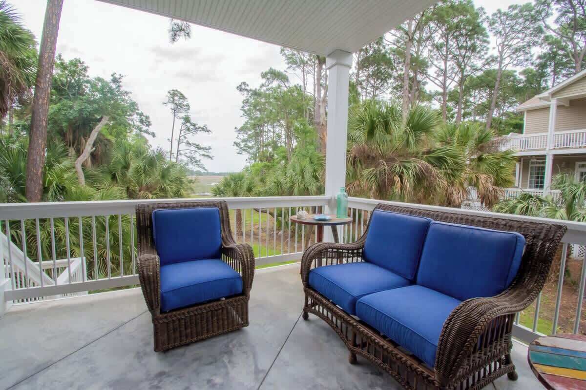 A covered outdoor area with wicker furniture and a view of the surrounding greenery.