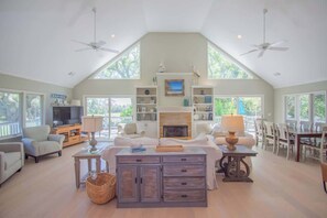 A spacious living room with a fireplace, a television, and a dining area with chairs and a table.