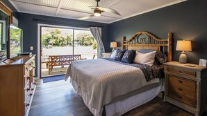A bedroom with a bed, bedside tables, a ceiling fan, and a view through a glass door. - 377 Tarpon Blvd (Fripp Island)