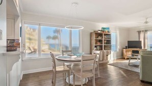 A spacious living area with a dining table, chairs, a bookshelf, a television, and a view of the outdoors. - 625 Newhaven (Fripp Island)