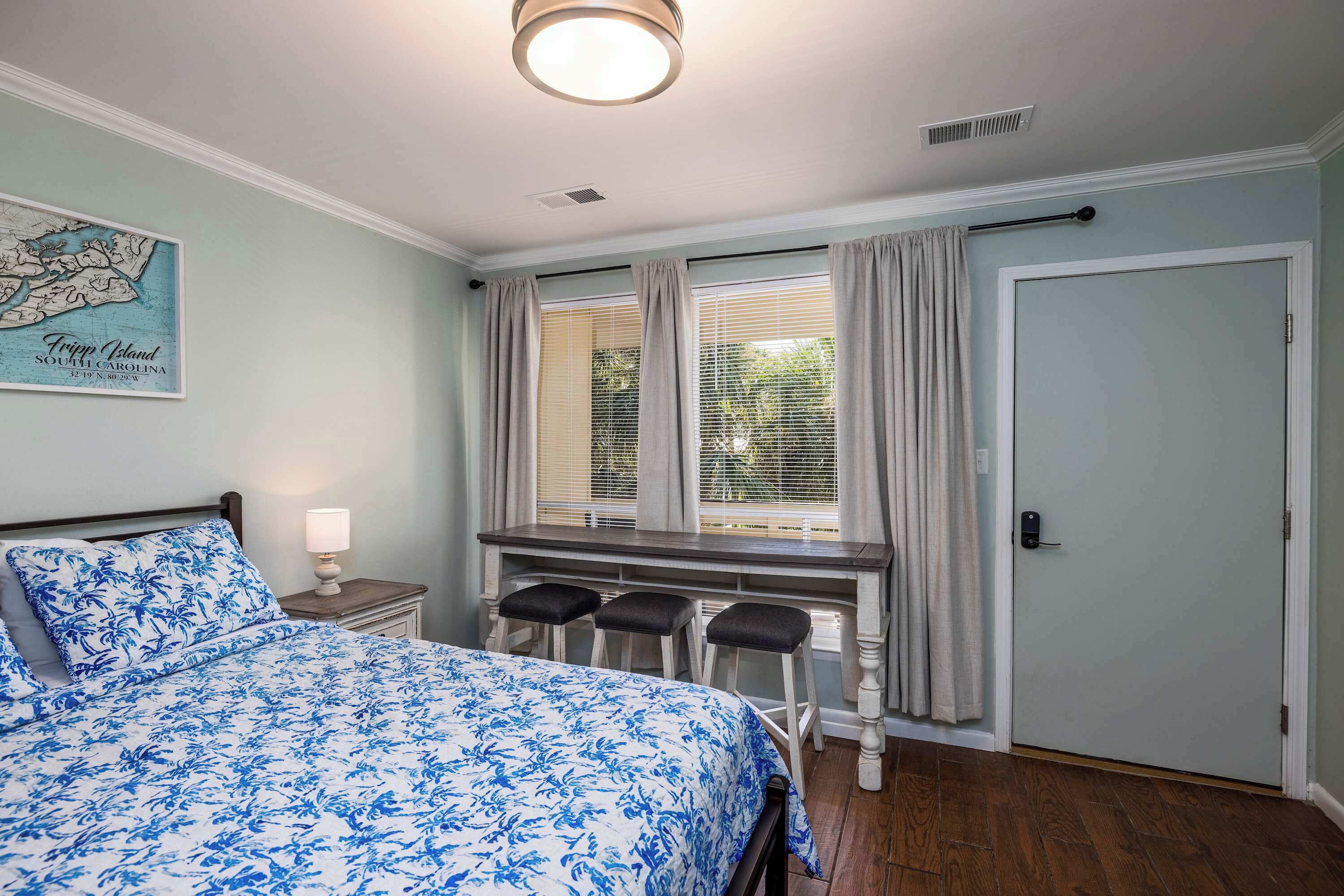 Une chambre à coucher avec un lit, un bureau avec des chaises, une carte accrochée au mur et une porte.