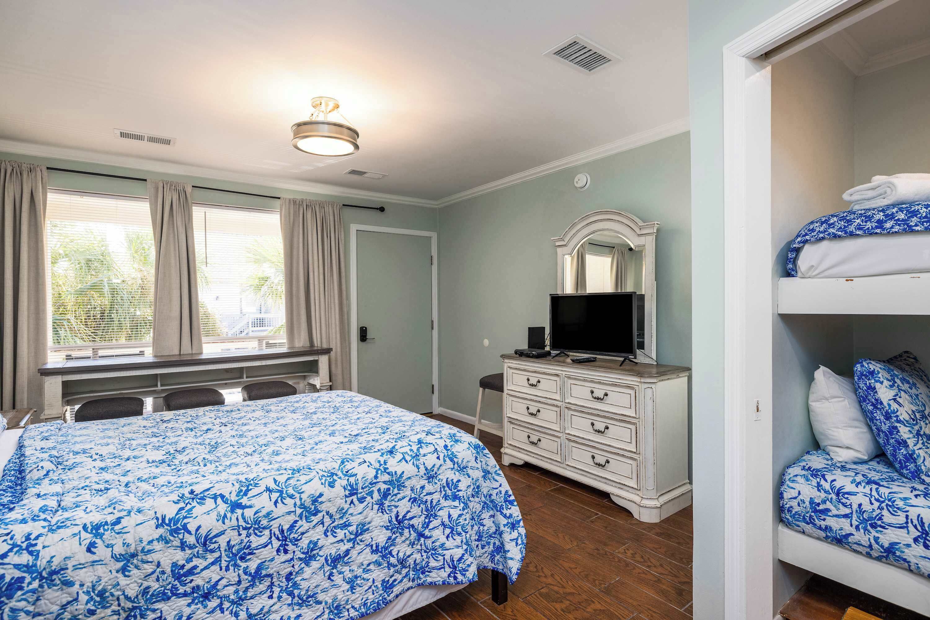A bedroom with a bed, a dresser, a television, and a closet.