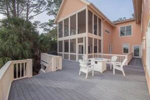 Une maison à deux étages dotée d’une grande terrasse, d’un espace extérieur couvert et offrant une vue sur les arbres environnants.