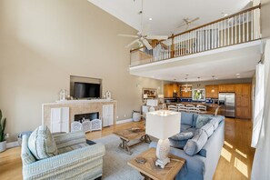 A spacious living room with a fireplace, a television, and a balcony with a railing.