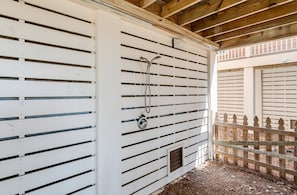 A white exterior wall with horizontal slats, a metal door with a handle, and a wooden fence. - 125 Ocean Creek Blvd (Fripp Island)