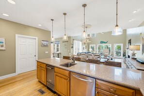 A kitchen with a central island, wooden cabinets, a stainless steel sink, and pendant lighting. - 125 Ocean Creek Blvd (Fripp Island)