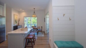 A kitchen with a central island, wooden stools, a hanging light fixture, and a bench with hooks on the wall. - 619 Porpoise Circle (Fripp Island)