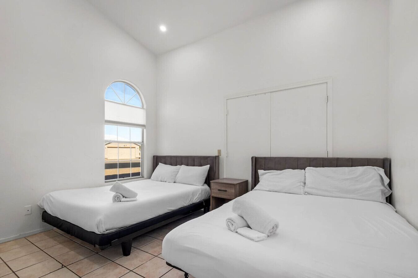 Ein Hotelzimmer mit zwei Betten, einem Fenster und Blick auf ein Gebäude.