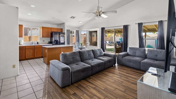 Una cocina moderna con armarios de madera, una isla central y una zona de comedor con mesa de vidrio.