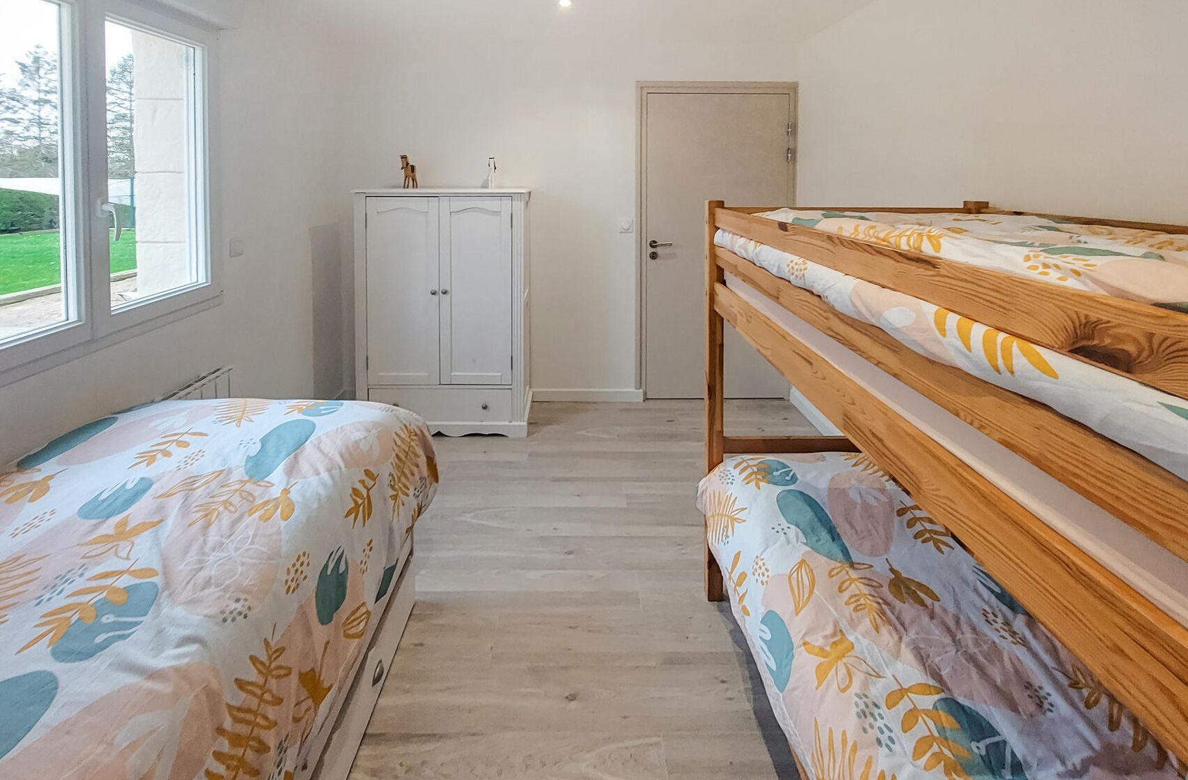 Un dormitorio con dos literas, un armario y una puerta que da a otra habitación.