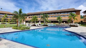 A hotel with a large swimming pool, palm trees, and lounge chairs. - Flat Eco Resort Praia dos Carneiros (Tamandaré)