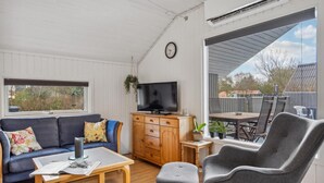 A cozy living room with a sofa, a coffee table, a television, and a dining area with a table and chairs.