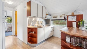 A modern kitchen with white and wooden cabinetry, a stainless steel sink, and a window providing a view of the outdoors.