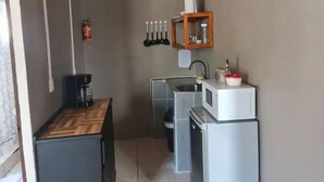 A compact kitchen with a microwave, sink, and a small cabinet.