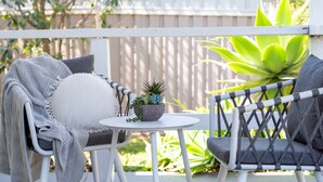 A patio with two chairs, a small table, and a potted plant.