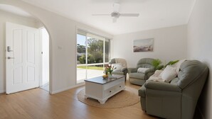 A spacious living room with a large window, a ceiling fan, and a view of the outdoors.