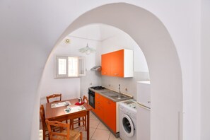 A compact kitchen with a dining area, a washing machine, and a window. - GuestHost - Casa Tosally with terrace (Ostuni)