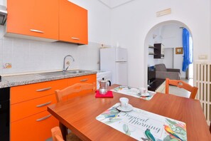 A kitchen with orange cabinets, a wooden dining table, and a coffee maker. - GuestHost - Casa Tosally with terrace (Ostuni)