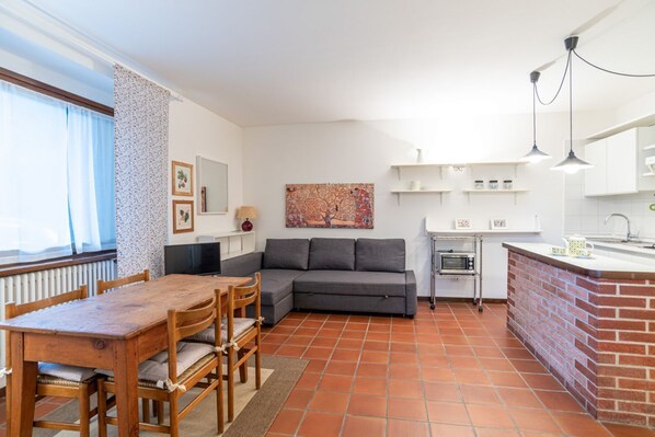 Un espace de vie compact comprenant un coin repas, un canapé, une cuisine et une grande fenêtre.