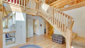 Une pièce spacieuse avec un escalier en bois, une armoire blanche et un petit tapis rond.