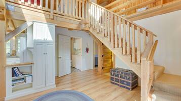 Une pièce spacieuse avec un escalier en bois, une armoire blanche et un petit tapis rond.
