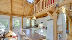 Une cuisine spacieuse avec un grand îlot central, des poutres en bois et un espace en mezzanine.