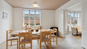 A dining area with a round table, chairs, and a window with a view of buildings.