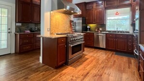 Una cocina con armarios de madera, una estufa de acero inoxidable y un horno empotrado.