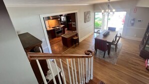 Una cocina amplia con electrodomésticos modernos, un comedor con candelabro y una escalera que sube a otro nivel.