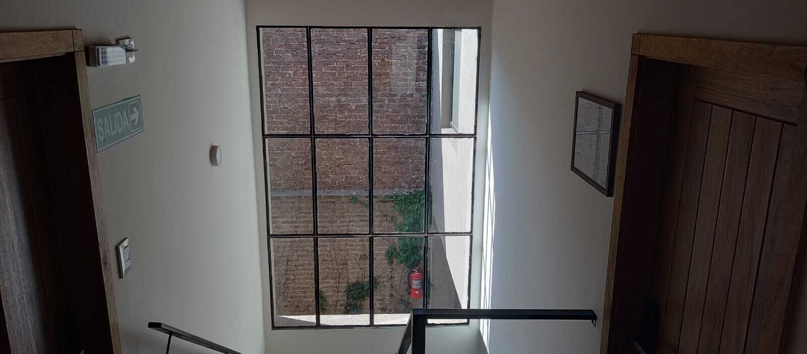 A stairwell with a view of a brick wall and a window.