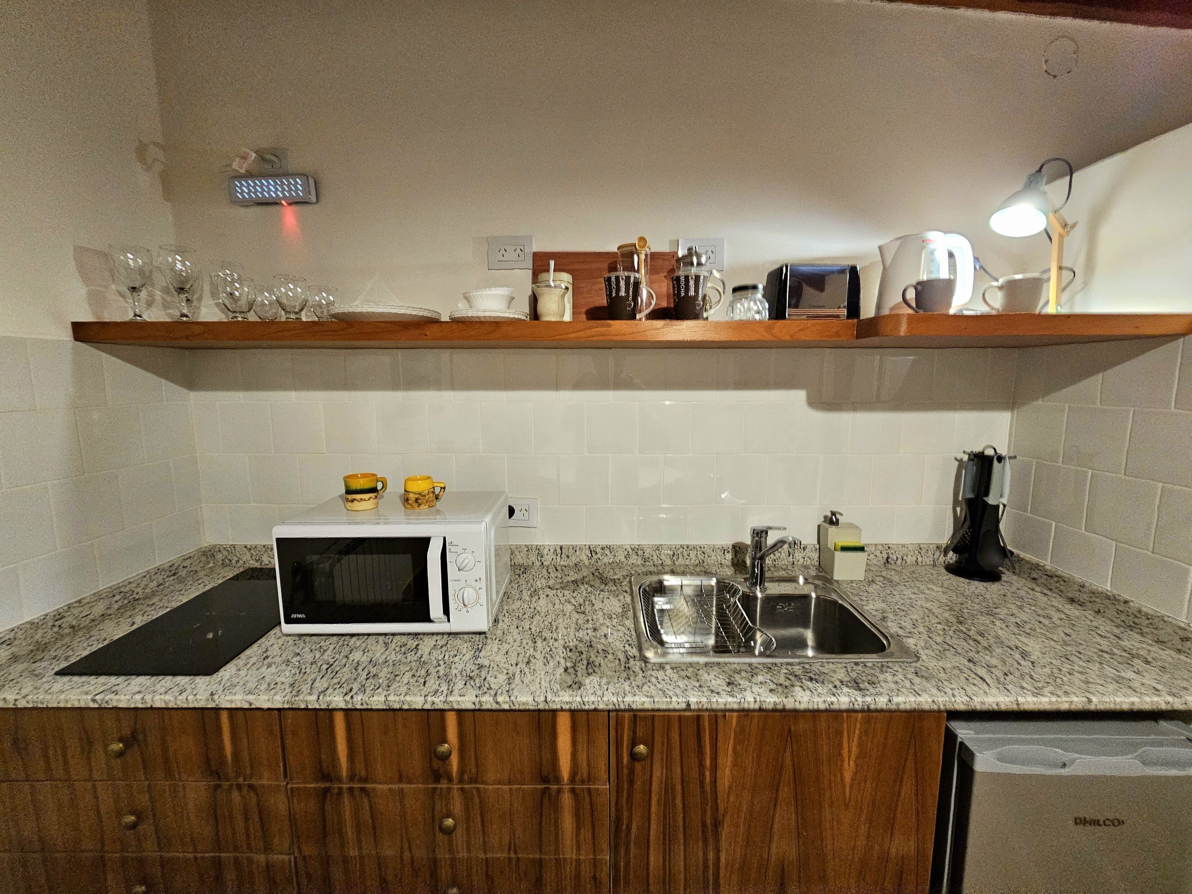 Cozinha com micro-ondas, pia e armários de madeira.