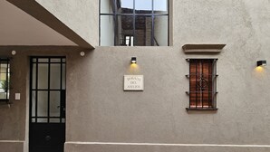 A building facade with a sign reading "POSADA DEL ATELIER," a black door, and two windows with metal bars. - Posada del Atelier (San Antonio de Areco)