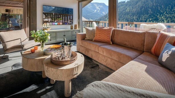 A cozy living area with a sofa, a coffee table, and a view of mountains.