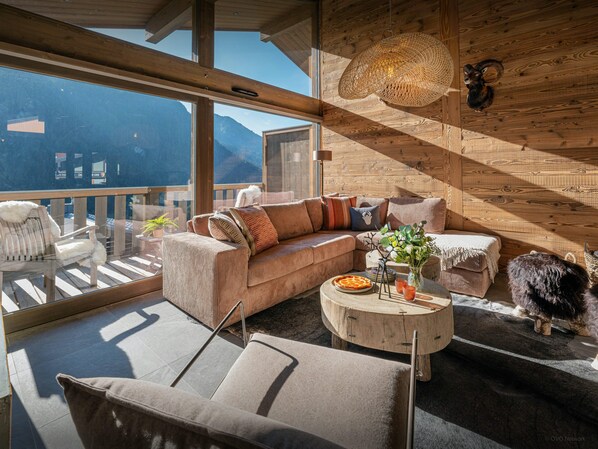 A cozy living room with a large window, a wooden ceiling, and a dog.