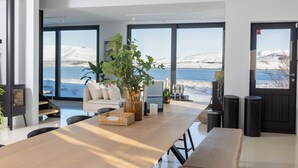 Ein modernes Interieur mit einem Holztisch, einer Couch und großen Fenstern mit Blick auf eine verschneite Landschaft.