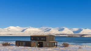 Ein modernes Holzhaus am See mit Bergblick.